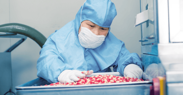 Asian GMP Operator inspecting capsules