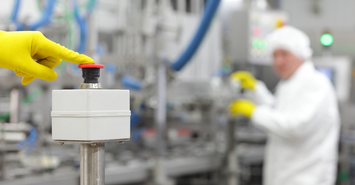 GMP operator pressing e-stop button on pharmaceutical processing equipment